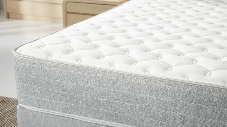 Side close‑up of the mattress edge, focusing on the quilted top layer and textured grey fabric Side close‑up of the mattress edge, focusing on the quilted top layer and textured grey fabric