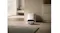 A low-profile robot vacuum approaches its dome-shaped dock A low-profile robot vacuum approaches its dome-shaped dock