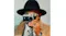 Person in a black hat and tan coat holding the camera to the eye Person in a black hat and tan coat holding the camera to the eye