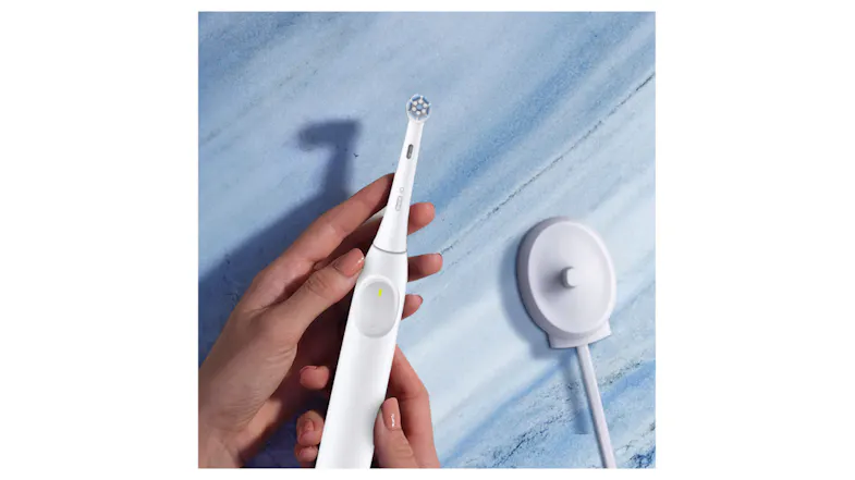 Close-up of hands holding the toothbrush near a charger Close-up of hands holding the toothbrush near a charger