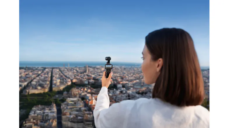 Over-the-shoulder view of a woman holding a camera over the city skyline Over-the-shoulder view of a woman holding a camera over the city skyline