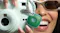 A green Tile Life360 Mate tracker clipped to a light blue instant camera held by a smiling person A green Tile Life360 Mate tracker clipped to a light blue instant camera held by a smiling person