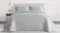 Front view of a queen bed styled with a ruched velvet coverlet in a soft silver‑grey tone Front view of a queen bed styled with a ruched velvet coverlet in a soft silver‑grey tone