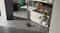 The robotic vacuum cleans food spills on a kitchen floor near a child’s high chair and a kitchen island The robotic vacuum cleans food spills on a kitchen floor near a child’s high chair and a kitchen island