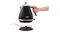 A hand lifts the De'Longhi kettle off its circular power base, demonstrating cordless use A hand lifts the De'Longhi kettle off its circular power base, demonstrating cordless use