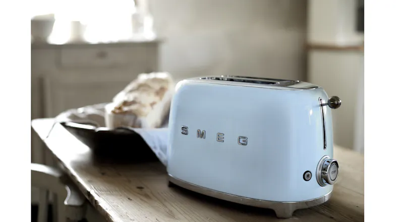 Angled view of a 2-slice toaster on a rustic wooden dining table Angled view of a 2-slice toaster on a rustic wooden dining table