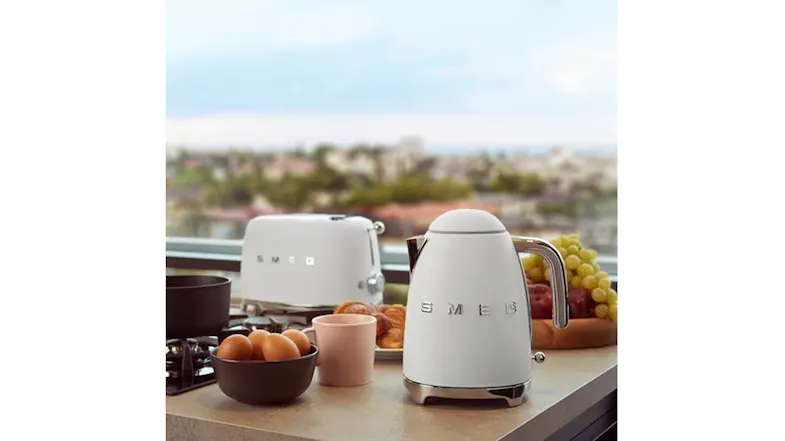 Kitchen counter scene featuring a matte white toaster and matching Smeg kettle beside eggs, cups, and a bowl Kitchen counter scene featuring a matte white toaster and matching Smeg kettle beside eggs, cups, and a bowl