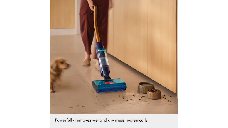 Person pushing the Dyson Clean+Wash Hygiene cleaner across a hard kitchen floor with pet food bowls nearby Person pushing the Dyson Clean+Wash Hygiene cleaner across a hard kitchen floor with pet food bowls nearby