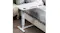 Modern white bedside desk with marble‑effect top, cup holder, and power cord positioned beside a bed Modern white bedside desk with marble‑effect top, cup holder, and power cord positioned beside a bed