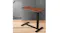 An adjustable side table with a wood grain top, cup holder, cable slot, and black steel T-frame base in a home office setting An adjustable side table with a wood grain top, cup holder, cable slot, and black steel T-frame base in a home office setting