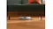Low-angle view of a white Roborock robotic vacuum cleaning a wooden floor beneath a sofa Low-angle view of a white Roborock robotic vacuum cleaning a wooden floor beneath a sofa