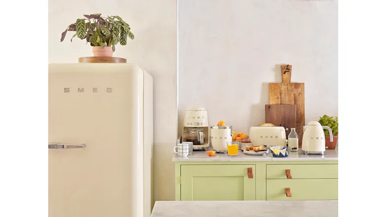 A close-up view of a green kitchen countertop with all of the available cream coloured Smeg appliances displayed A close-up view of a green kitchen countertop with all of the available cream coloured Smeg appliances displayed