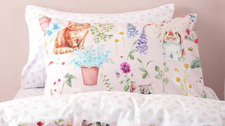 A close-up of the bedding showing a matching pillowcase with an orange tabby cat and a fluffy rabbit A close-up of the bedding showing a matching pillowcase with an orange tabby cat and a fluffy rabbit