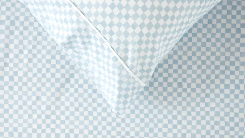 A top-down view of the bedding featuring the slightly irregular lines of the blue and white checkered print A top-down view of the bedding featuring the slightly irregular lines of the blue and white checkered print