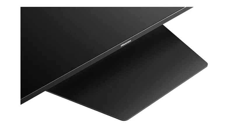 Close‑up of the lower bezel with the Hisense logo and the wide, flat stand base beneath the screen Close‑up of the lower bezel with the Hisense logo and the wide, flat stand base beneath the screen