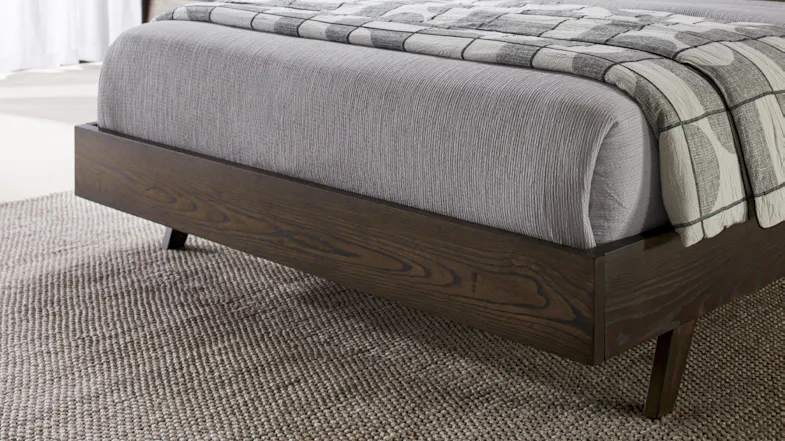 Low-angle view of the dark wood frame and tapered cylindrical legs Low-angle view of the dark wood frame and tapered cylindrical legs