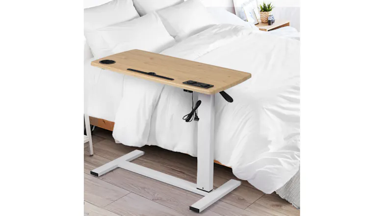 Adjustable side table positioned beside a bed, demonstrating use as an over‑bed or bedside table Adjustable side table positioned beside a bed, demonstrating use as an over‑bed or bedside table