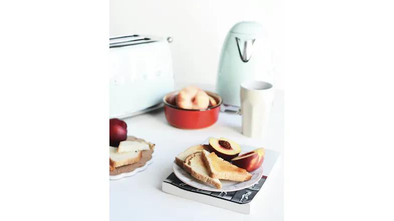 Pastel green toaster and kettle behind a plate of toast and peaches Pastel green toaster and kettle behind a plate of toast and peaches