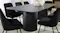 Close-up of the extended black table highlighting curved edges, with several upholstered chairs visible Close-up of the extended black table highlighting curved edges, with several upholstered chairs visible