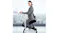 Person using a kneeling chair at a standing desk while typing on a laptop in an office setting Person using a kneeling chair at a standing desk while typing on a laptop in an office setting