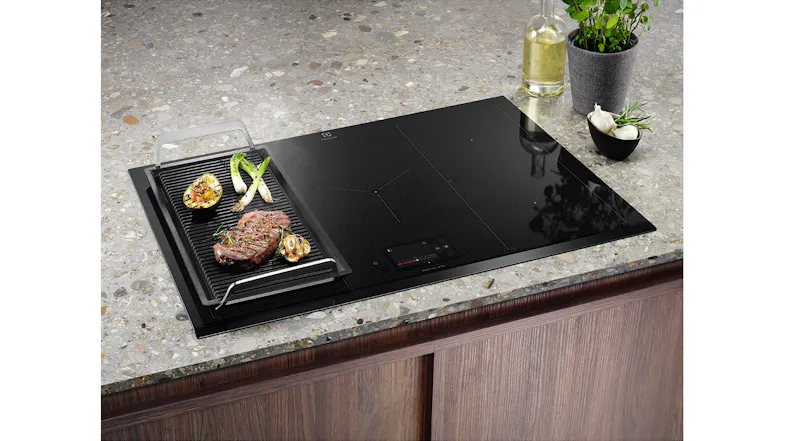 The induction cooktop with a grill plate placed over one cooking zone The induction cooktop with a grill plate placed over one cooking zone