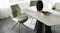 Close-up of the oval tabletop with soft edges and subtle texture, paired with an olive fabric chair Close-up of the oval tabletop with soft edges and subtle texture, paired with an olive fabric chair