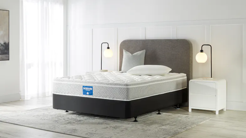 Modern bedroom setup featuring an Incredi‑Bed medium mattress on a dark base with an upholstered headboard and bedside lamps Modern bedroom setup featuring an Incredi‑Bed medium mattress on a dark base with an upholstered headboard and bedside lamps