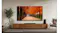 Living room with a TV displaying an autumn tree-lined path, with a soundbar and speakers below Living room with a TV displaying an autumn tree-lined path, with a soundbar and speakers below