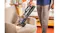 Handheld vacuum tool cleaning fabric armchair seat with LED lights, as crumbs and pet toys sit nearby in a cosy living room Handheld vacuum tool cleaning fabric armchair seat with LED lights, as crumbs and pet toys sit nearby in a cosy living room
