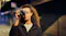 Person holding a camera to their eye, taking a photo at night with blurred street lights in the background Person holding a camera to their eye, taking a photo at night with blurred street lights in the background
