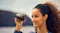 A person holding a Lumix camera with an extended zoom lens, aiming to take a photo outdoors near a large body of water A person holding a Lumix camera with an extended zoom lens, aiming to take a photo outdoors near a large body of water