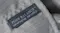 A dark woven tag on a grey modal sheet, branded quality marker indicating temperature-regulating bedding technology A dark woven tag on a grey modal sheet, branded quality marker indicating temperature-regulating bedding technology