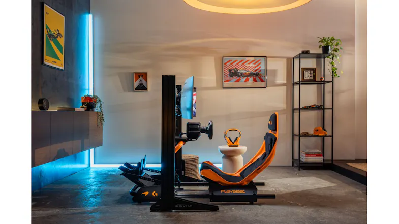 Wide side view of an orange racing seat, highlighting F1 wall art Wide side view of an orange racing seat, highlighting F1 wall art