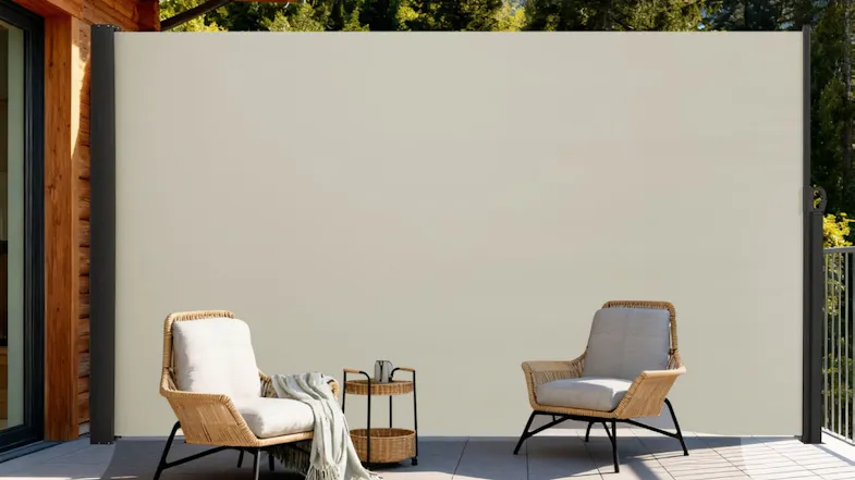 A side awning installed beside a modern house, extended across a patio to block the sun and wind while facing a green garden A side awning installed beside a modern house, extended across a patio to block the sun and wind while facing a green garden