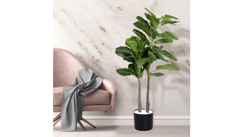 Decorative faux fiddle leaf fig tree with lush green leaves in a black pot next to a chair in a modern living room Decorative faux fiddle leaf fig tree with lush green leaves in a black pot next to a chair in a modern living room