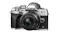 A silver Olympus OM‑D camera with a 17mm lens, textured grip, and control dials A silver Olympus OM‑D camera with a 17mm lens, textured grip, and control dials
