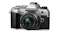 Silver OM System OM‑5 camera with attached 17mm lens, showing textured grip and control dials Silver OM System OM‑5 camera with attached 17mm lens, showing textured grip and control dials