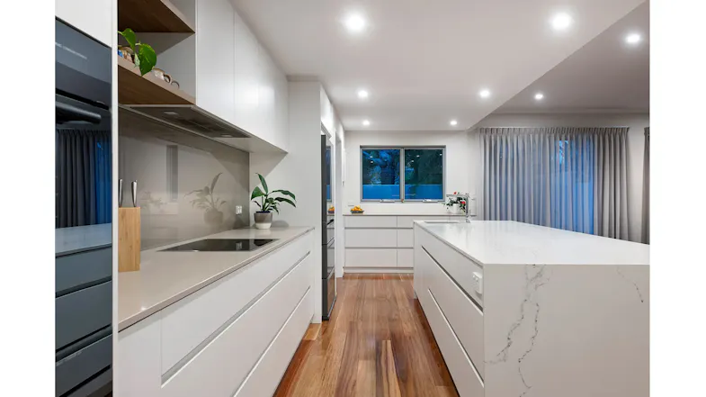 Contemporary kitchen with countertop, white cabinetry, cooktop, window, and integrated Schweigen undermount rangehood Contemporary kitchen with countertop, white cabinetry, cooktop, window, and integrated Schweigen undermount rangehood
