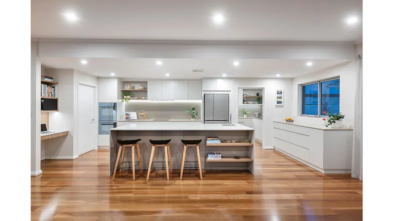Wide view of a modern kitchen with countertop chairs, built-in appliances, wood floors, and concealed Schweigen rangehood Wide view of a modern kitchen with countertop chairs, built-in appliances, wood floors, and concealed Schweigen rangehood