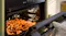 A built-in Haier steam oven with open door roasting seasoned potato wedges on a tray A built-in Haier steam oven with open door roasting seasoned potato wedges on a tray