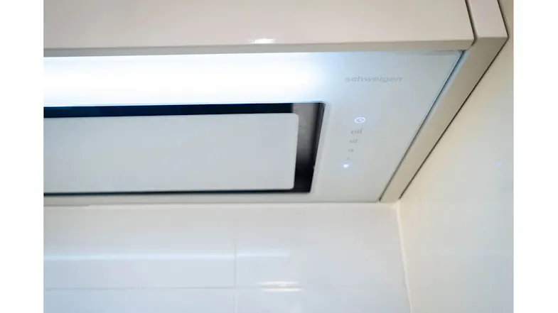 Modern white kitchen with a built-in rangehood, smooth cabinets, stovetop, and wall ovens Modern white kitchen with a built-in rangehood, smooth cabinets, stovetop, and wall ovens
