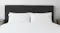 Nile upholstered headboard in black finish with vertical panels, styled with white bedding in a modern bedroom Nile upholstered headboard in black finish with vertical panels, styled with white bedding in a modern bedroom