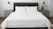 Minimalist bedroom with neatly made white bed with headboard, wooden nightstands, black lamps, and small plants Minimalist bedroom with neatly made white bed with headboard, wooden nightstands, black lamps, and small plants