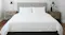 Minimalist bedroom with neatly made white bed with headboard, wooden nightstands, black lamps, and small plants Minimalist bedroom with neatly made white bed with headboard, wooden nightstands, black lamps, and small plants