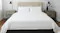 Minimalist bedroom with neatly made white bed with headboard, wooden nightstands, black lamps, and small plants Minimalist bedroom with neatly made white bed with headboard, wooden nightstands, black lamps, and small plants