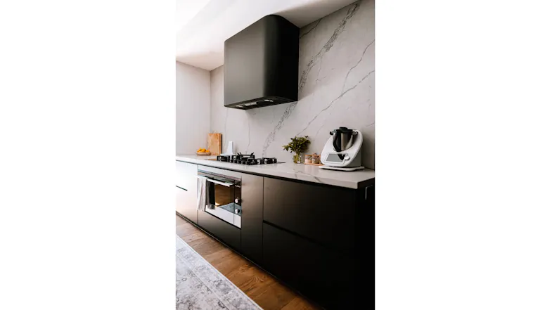 Kitchen interior with black rangehood, gas cooktop, and modern stone surfaces Kitchen interior with black rangehood, gas cooktop, and modern stone surfaces