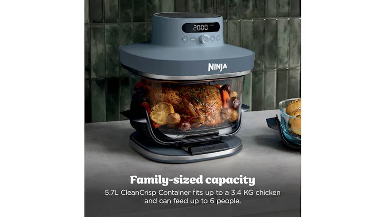 Ninja Crispi Pro air fryer on a kitchen countertop with a glass bowl holding a roasted whole chicken and vegetables Ninja Crispi Pro air fryer on a kitchen countertop with a glass bowl holding a roasted whole chicken and vegetables