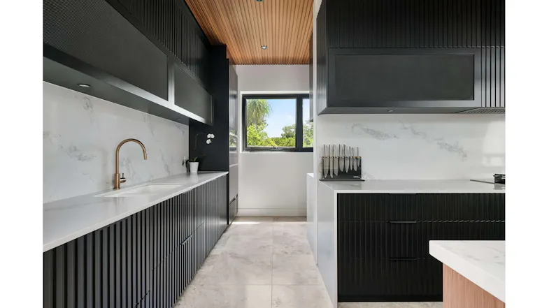 Contemporary kitchen with black panelled cabinets, marble backsplash, window view and built-in undermount rangehood area Contemporary kitchen with black panelled cabinets, marble backsplash, window view and built-in undermount rangehood area