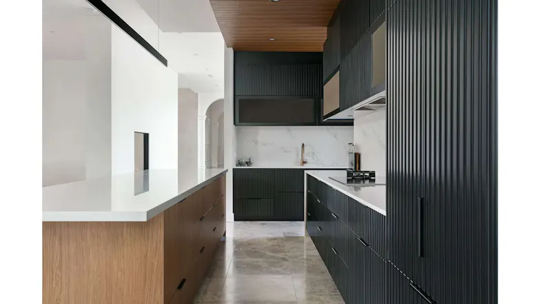 Modern kitchen interior with black cabinetry, white countertops, wooden ceiling and integrated undermount rangehood setup Modern kitchen interior with black cabinetry, white countertops, wooden ceiling and integrated undermount rangehood setup