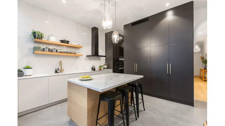 Contemporary kitchen interior with marble countertop island, black cabinetry, gold handles, and pendant lights Contemporary kitchen interior with marble countertop island, black cabinetry, gold handles, and pendant lights